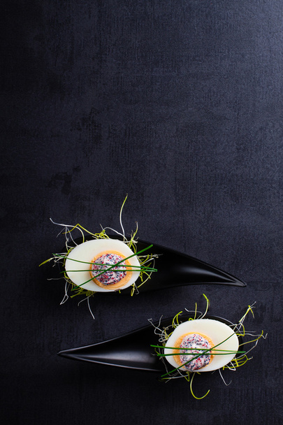 Vorspeise auf Fingerlöffel-Ei mit Kaviaron schwarzem Hintergrund. - Foto, Bild
