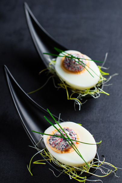 Appetizer on fingerspoon egg with caviaron black background. - Photo, Image