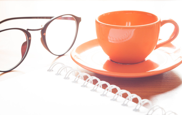 Close up of coffee cup with book and eyeglasses - Foto, afbeelding