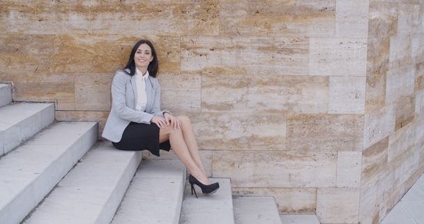 businesswoman sitting on marble stairs outdoors - Fotó, kép