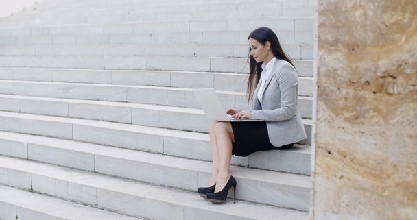 businesswoman sitting on marble staircase with laptop - Photo, Image