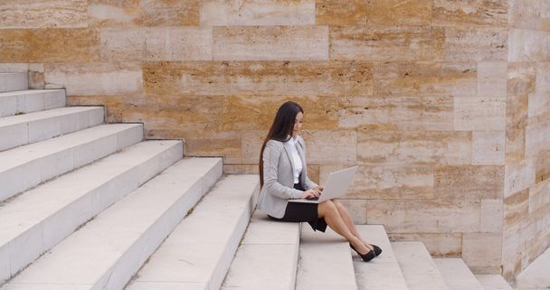 mujer de negocios sentada en una escalera de mármol con portátil
 - Foto, imagen
