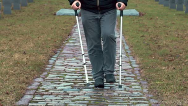 Vammainen veteraani kainalosauvoilla kävelemässä hautausmaalla
 - Materiaali, video