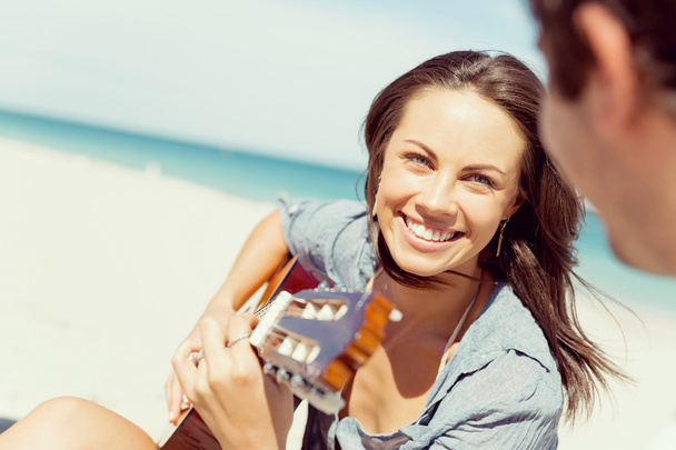 Beautiful young woman playing guitar on beach - Фото, изображение