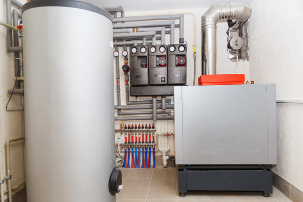 Uma sala de caldeira doméstica com um novo sistema moderno de aquecimento de água quente de óleo e tubos
 - Foto, Imagem