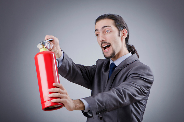 Man with fire extinguisher in firefighting concept - Foto, Imagen