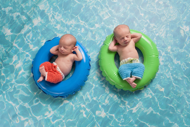 Мальчики-близнецы плавают на плавающих кольцах
 - Фото, изображение