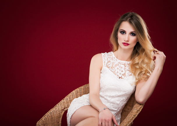 Blond seducive beautiful woman in white dress sitting in the arm - Fotó, kép