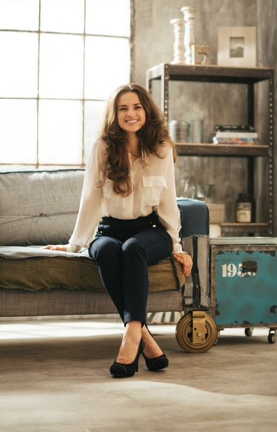 Smiling brunet woman in elegant clothing sitting in loft room - Foto, immagini
