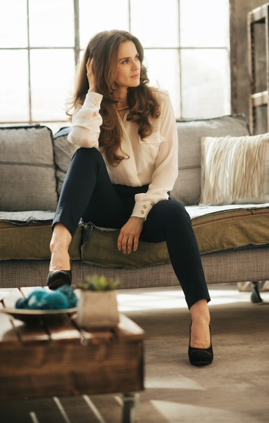 Young elegant woman with brown hairs sitting in loft apartment - Фото, зображення