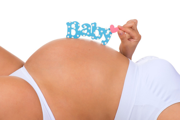 Terhesség. Közelkép belly terhes nő. Kék címkés újszülött fiú. - Fotó, kép