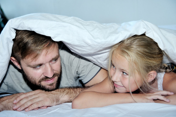 Sorrindo pai e sua filha se divertindo deitado em uma cama
 - Foto, Imagem