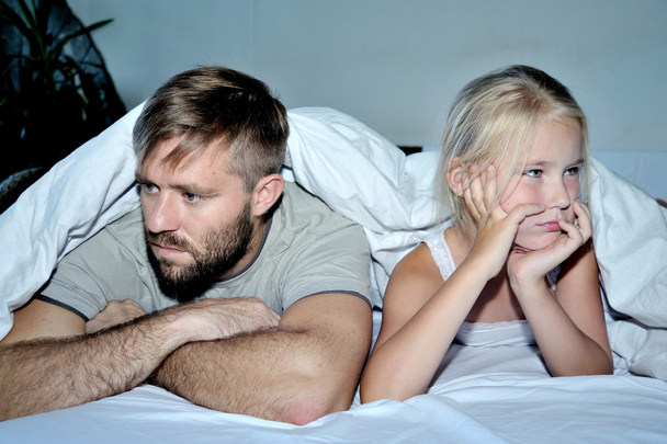 Portrait of displeased father  daughter  together lying on bed  - Photo, Image