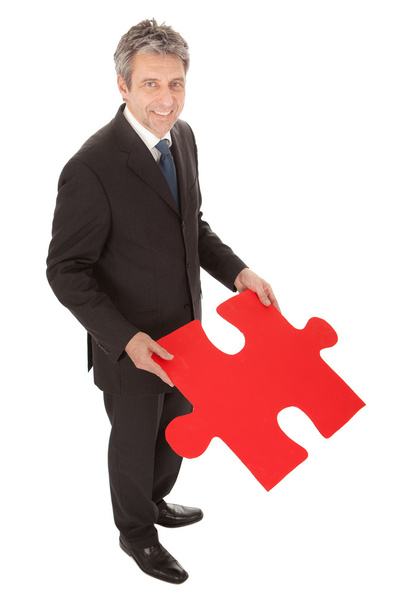 Senior businessman holding a jigsaw puzzle - Foto, immagini
