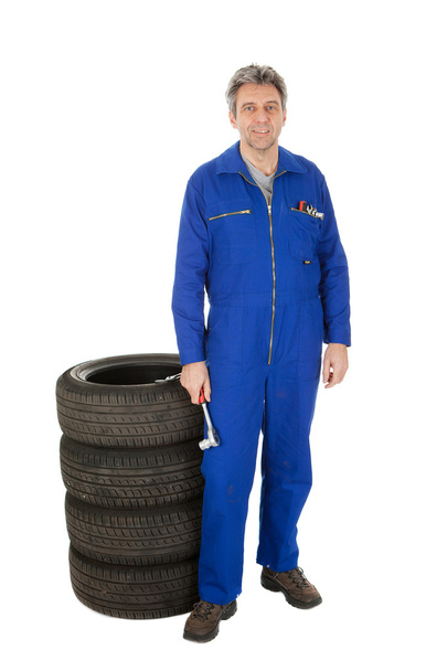 Automechanic standing next to car tires - Foto, imagen