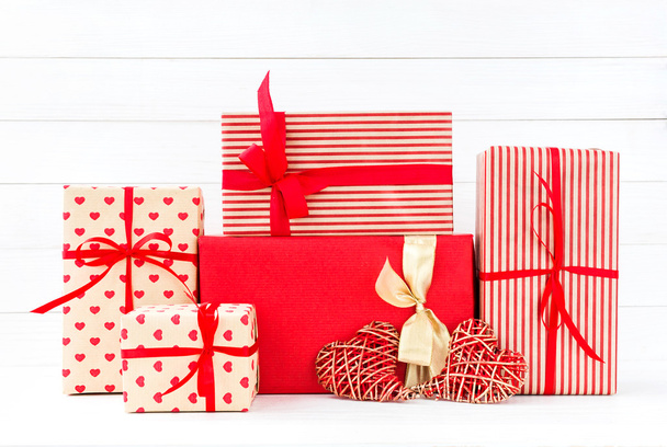 Envuelto cajas de regalos y dos corazones rojos sobre fondo de madera blanca
 - Foto, imagen