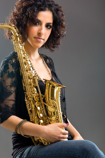 schönes Mädchen mit Saxophon auf grauem Hintergrund - Foto, Bild