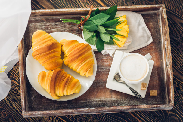 Coffee, croissant and flowers on tray on a wooden table - Photo, Image