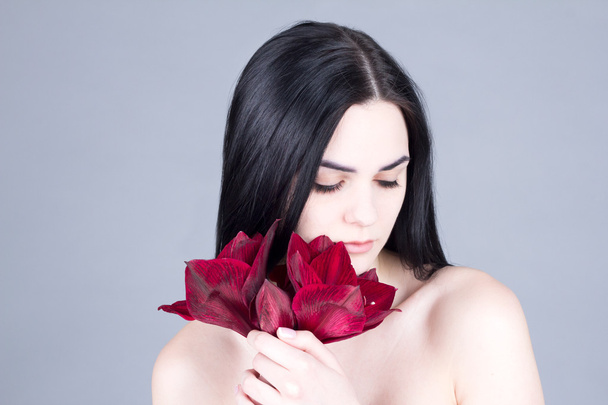 Portrait of a beautiful brunette, looking down with a bouquet of red flowers - Φωτογραφία, εικόνα