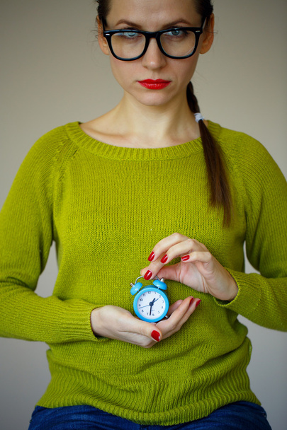 Kleine blauwe alarm klok in de handen van een emotionele jonge vrouw - Foto, afbeelding