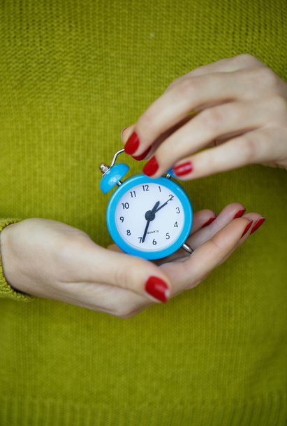 Kleine blauwe alarm klok in de handen van vrouw - Foto, afbeelding