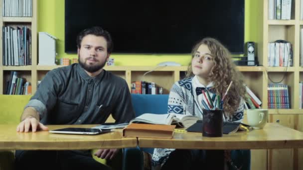 pareja de estudiantes sentados en la sala de clases y mirando a la cámara
 - Metraje, vídeo