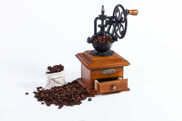 an old hand grinder for grinding coffee beans, roasted coffee beans on a white background. - Фото, изображение