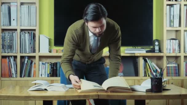 estudiante masculino que busca la información necesaria en los libros de cámara lenta
 - Imágenes, Vídeo
