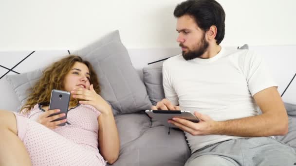 erkek ve kadın yatakta smartphone ve tablet yavaş hareket kullanma - Video, Çekim