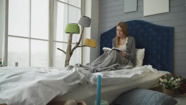 Blonde reading a book while sitting in bed. - Footage, Video