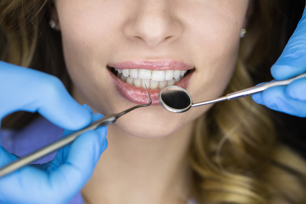 Dentist examining a patients teeth in the dentist. - Zdjęcie, obraz