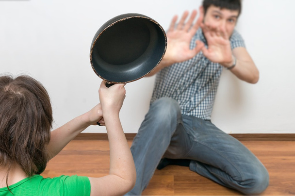 Wife is attacking her husband with a frying pan. Domestic violence concept. - Photo, Image