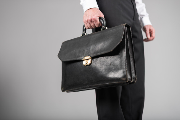 Businessman standing and holding a briefcase - Foto, afbeelding