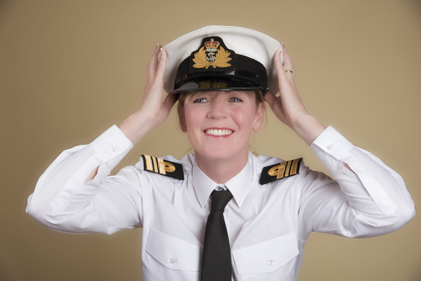 Female naval officer placing her hat onto her head - Photo, Image