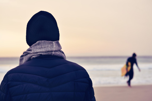 homme vêtu d'un manteau, d'une écharpe et d'un bonnet en tricot devant l'océan
 - Photo, image