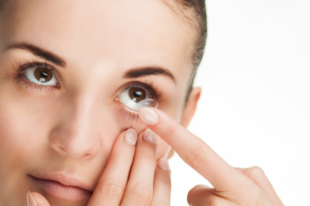 Woman putting contact lens in her eye - Foto, afbeelding