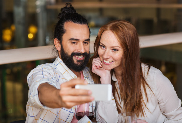 couple taking selfie by smartphone at restaurant - Fotografie, Obrázek