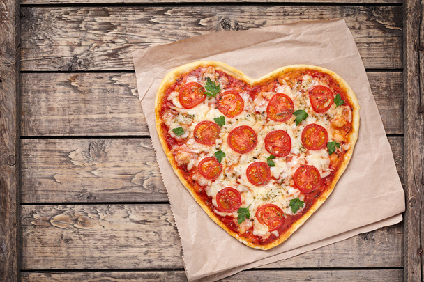 Heart shaped pizza margherita with tomatoes and mozzarella for Valentines Day on vintage wooden background. Food concept of romantic love. - Foto, afbeelding