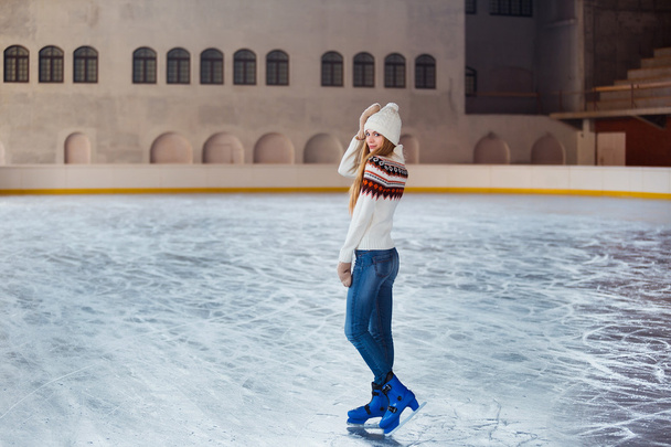 Young woman dressed in a warm woolen cardigan, gloves and hat posing outside at skating park - 写真・画像