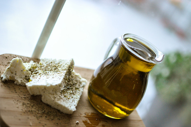 close up of feta cheese(Greek cheese) slices on a wooden serving board and a bottle of olive oil in nature light - Photo, image