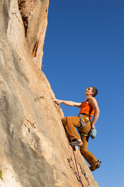 Jonge mannelijke klimmer opknoping door een klif. - Foto, afbeelding