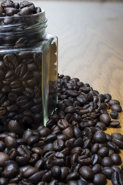Coffee beans in transparent jar and on wooden table. - Photo, Image