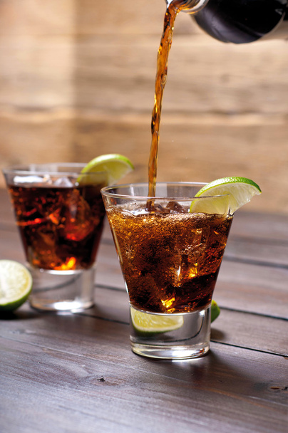 Pour the rum and cola cuba libre with lime, ice - Фото, изображение