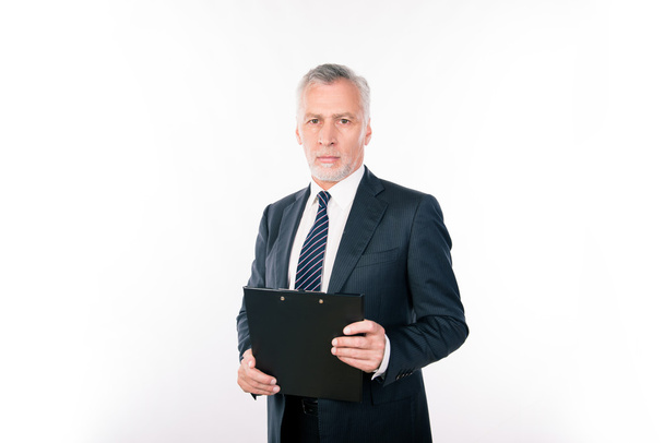  Calm aged focused man working with clipboard - 写真・画像