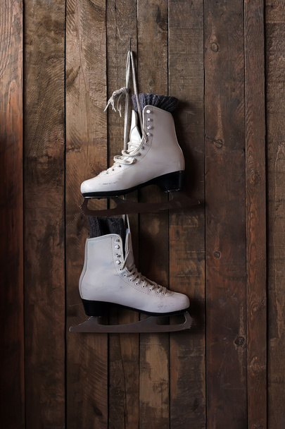 The female white skates hang on a nail against from boards. - 写真・画像