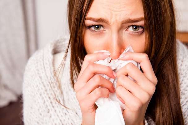 Close up portrait of sick woman  with fever sneezing in tissue - 写真・画像