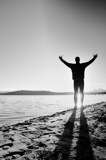Silhouette des sportlichen aktiven erwachsenen Mannes, der am Strand läuft und Sport treibt. ruhiges Wasser, Insel und Sonnenuntergang Himmel Hintergrund. - Foto, Bild