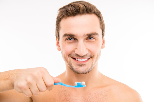 Handsome man holding a toothbrus - Foto, imagen