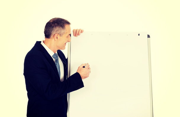 Male executive writing on a flipchart - Фото, изображение
