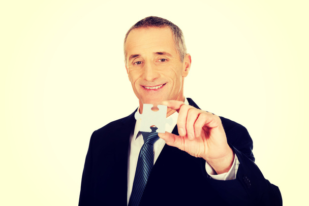 Smart businessman holding a puzzle - Photo, image